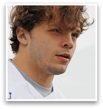 A man wearing a white and blue shirt with a logo of a shark. Description generated by AI