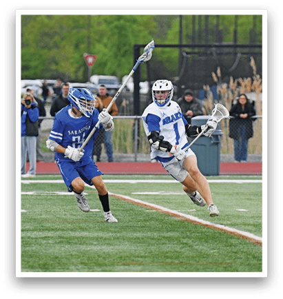 A man in a blue and white uniform is running with a lacrosse stick. Description generated by AI