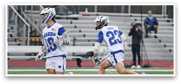 Two lacrosse players running on a field. Description generated by AI