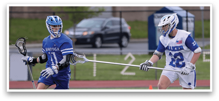 Two men playing lacrosse on a field. Description generated by AI