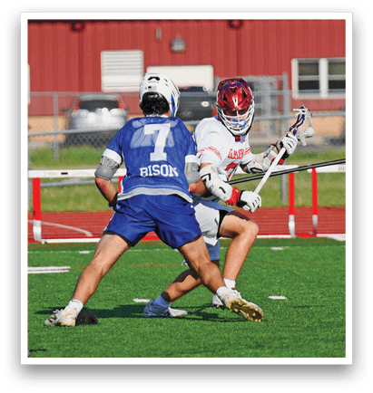 A man in a blue shirt and white shorts is playing lacrosse. Description generated by AI