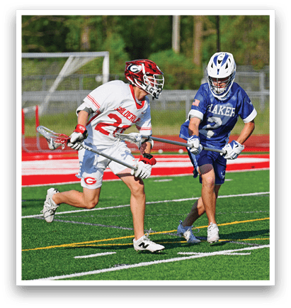 Two men playing lacrosse on a field. Description generated by AI