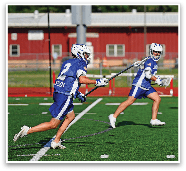Two men playing lacrosse on a field. Description generated by AI