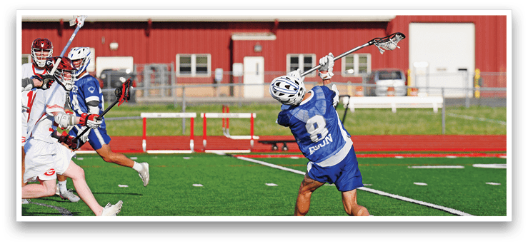 A man in a blue shirt and white shorts is playing lacrosse. Description generated by AI