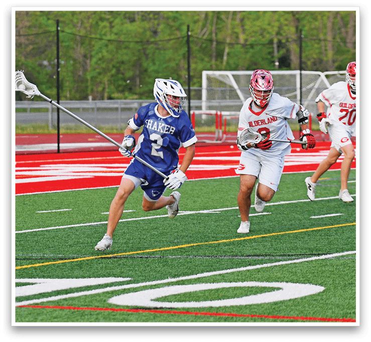 A man in a blue and white uniform is running with a lacrosse stick. Description generated by AI