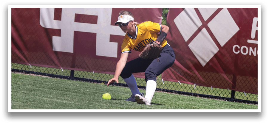 A woman wearing a yellow shirt and black pants is bending over to catch a ball. Description generated by AI