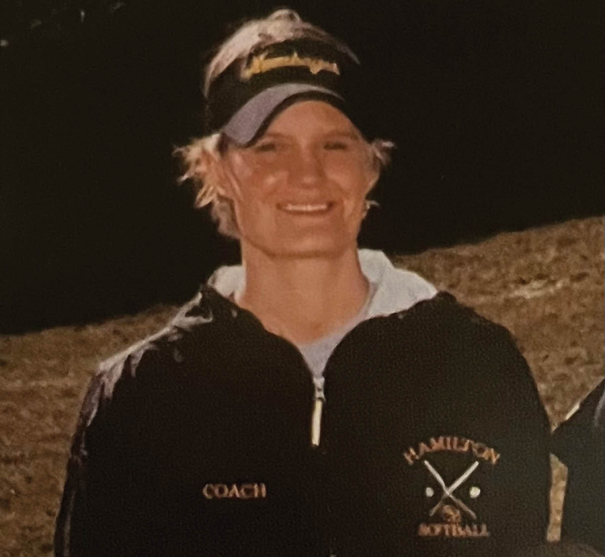 A woman wearing a black jacket and a baseball cap stands next to a girl with blonde hair. AI generated content