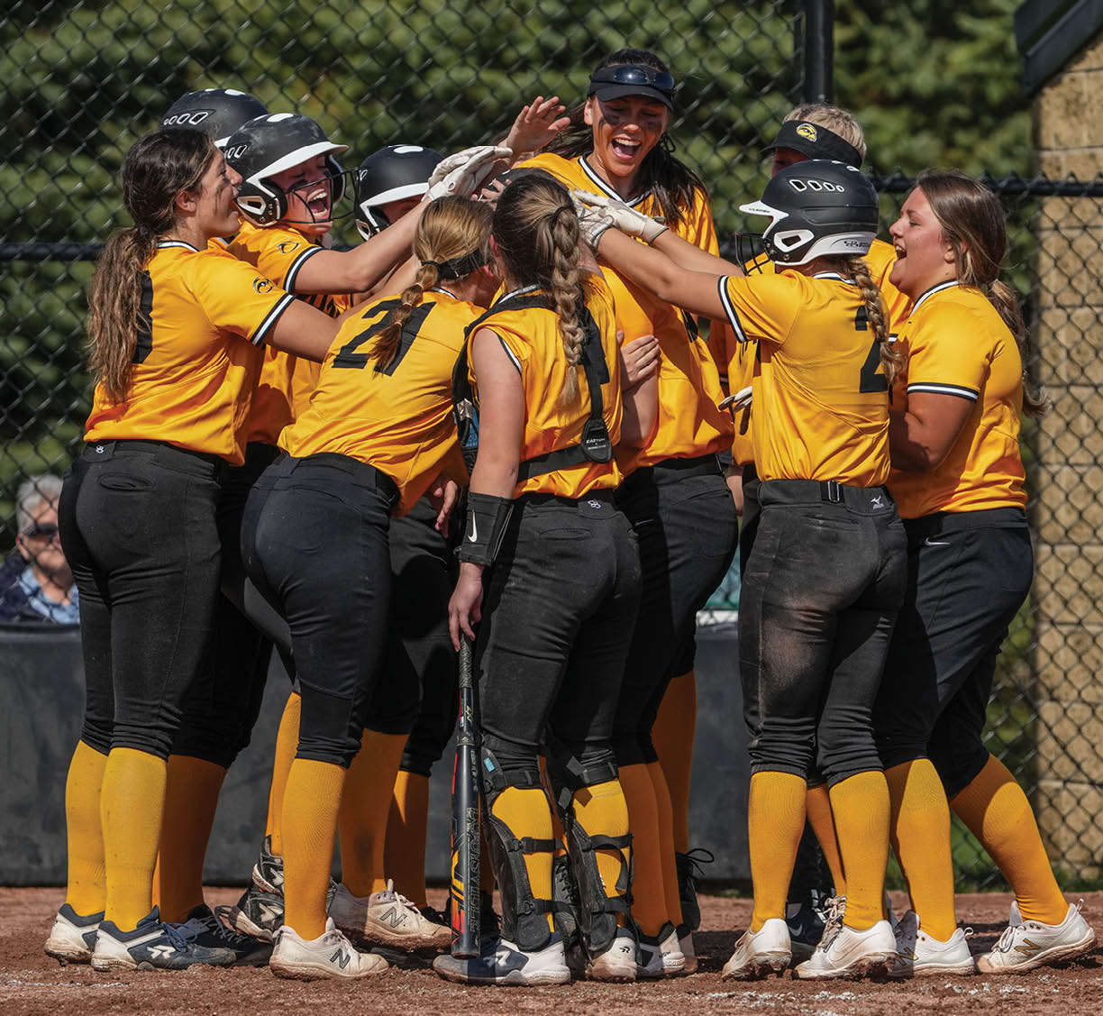 A group of female softball players hugging each other on the field. AI generated content