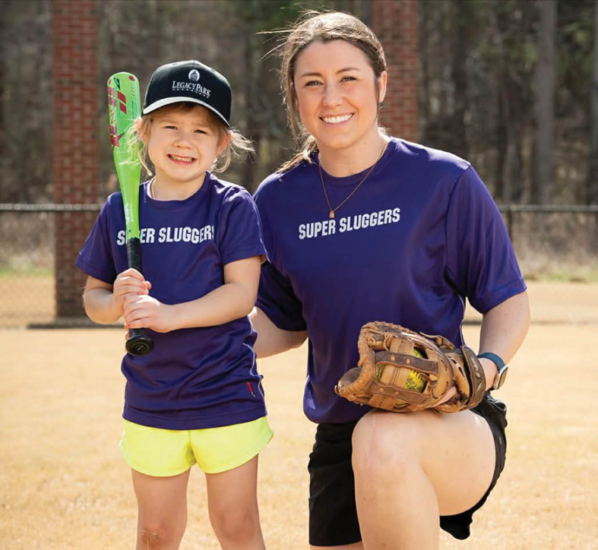 A woman and a girl are standing on a field, both holding baseball bats. The woman is wearing a purple shirt and a baseball glove. AI generated content