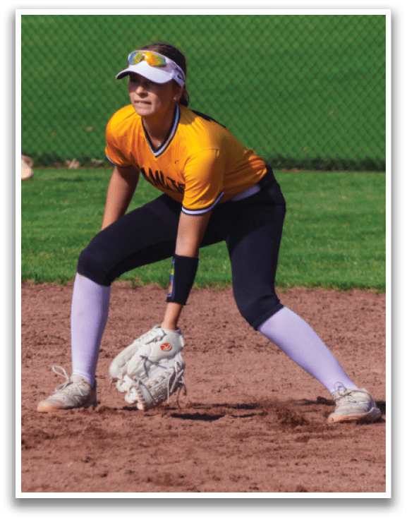 A woman in a yellow shirt is playing softball, holding a catcher's mitt and preparing to catch a ball. AI generated content