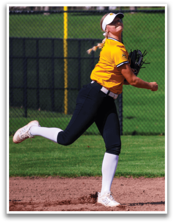 A woman in a yellow shirt and black pants is pitching a softball. AI generated content