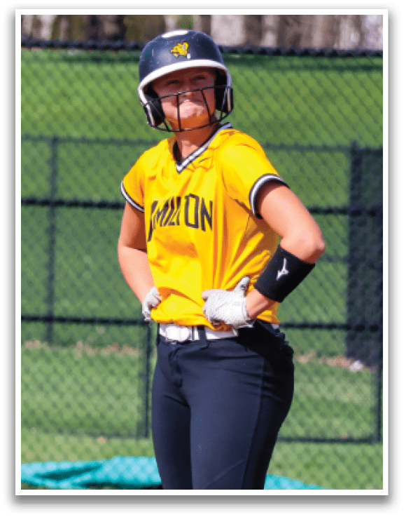 A female baseball player wearing a yellow and black uniform stands on the field. AI generated content