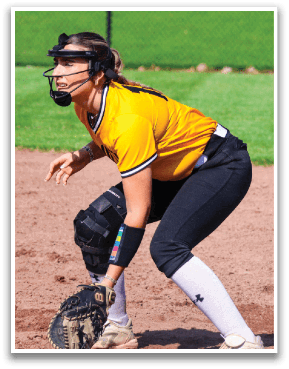 A female baseball player in a yellow shirt and black pants is crouched down, wearing a helmet and holding a baseball glove. AI generated content