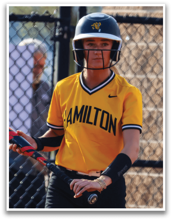 A young woman in a yellow shirt and black helmet is holding a baseball bat, getting ready to play. AI generated content