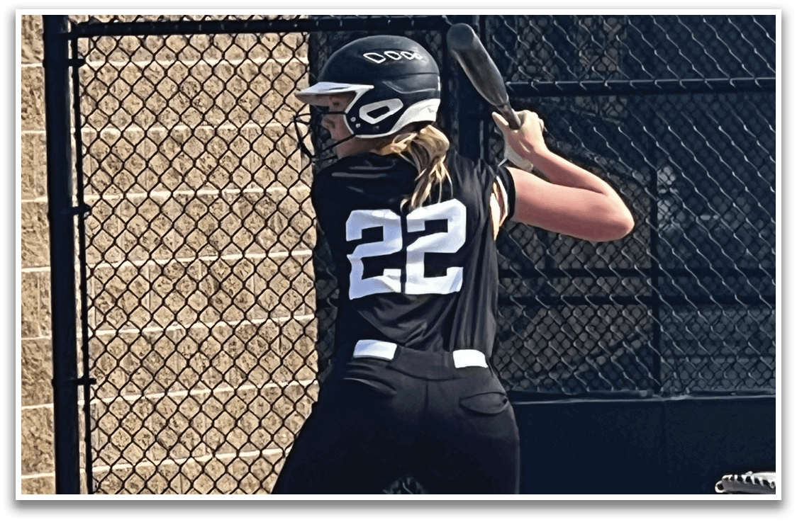 A woman in a black and white uniform is holding a baseball bat, preparing to swing at a pitch. AI generated content