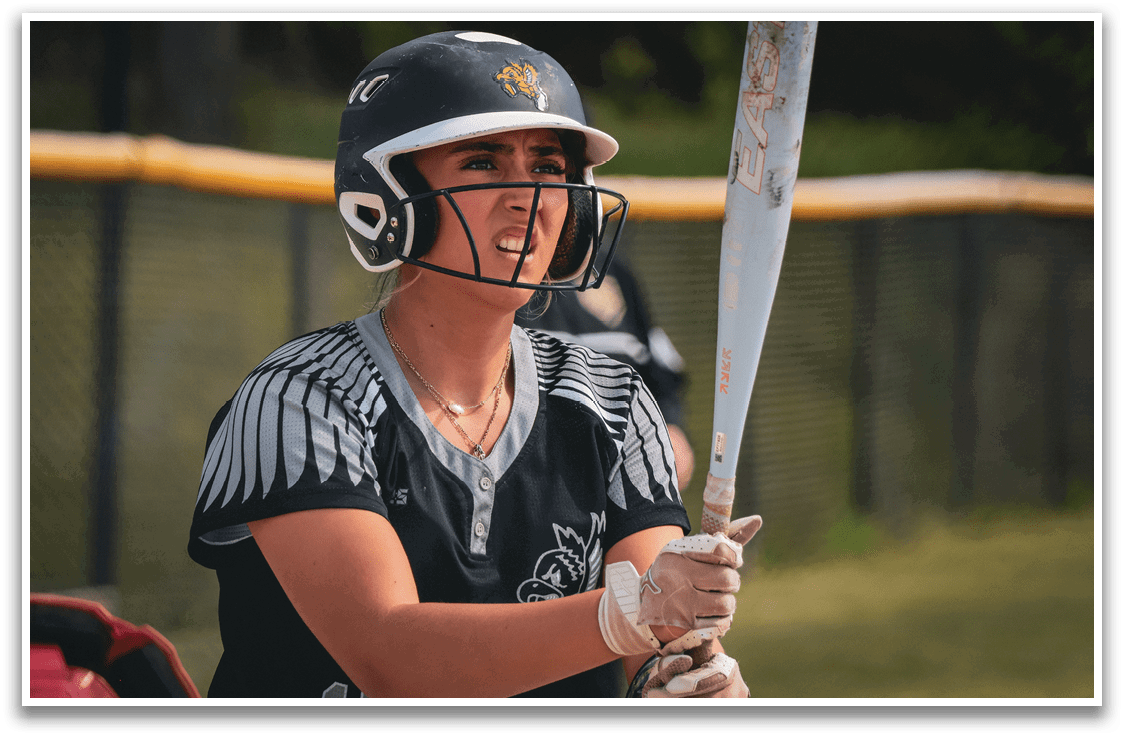 A woman wearing a helmet and holding a baseball bat. Description generated by AI