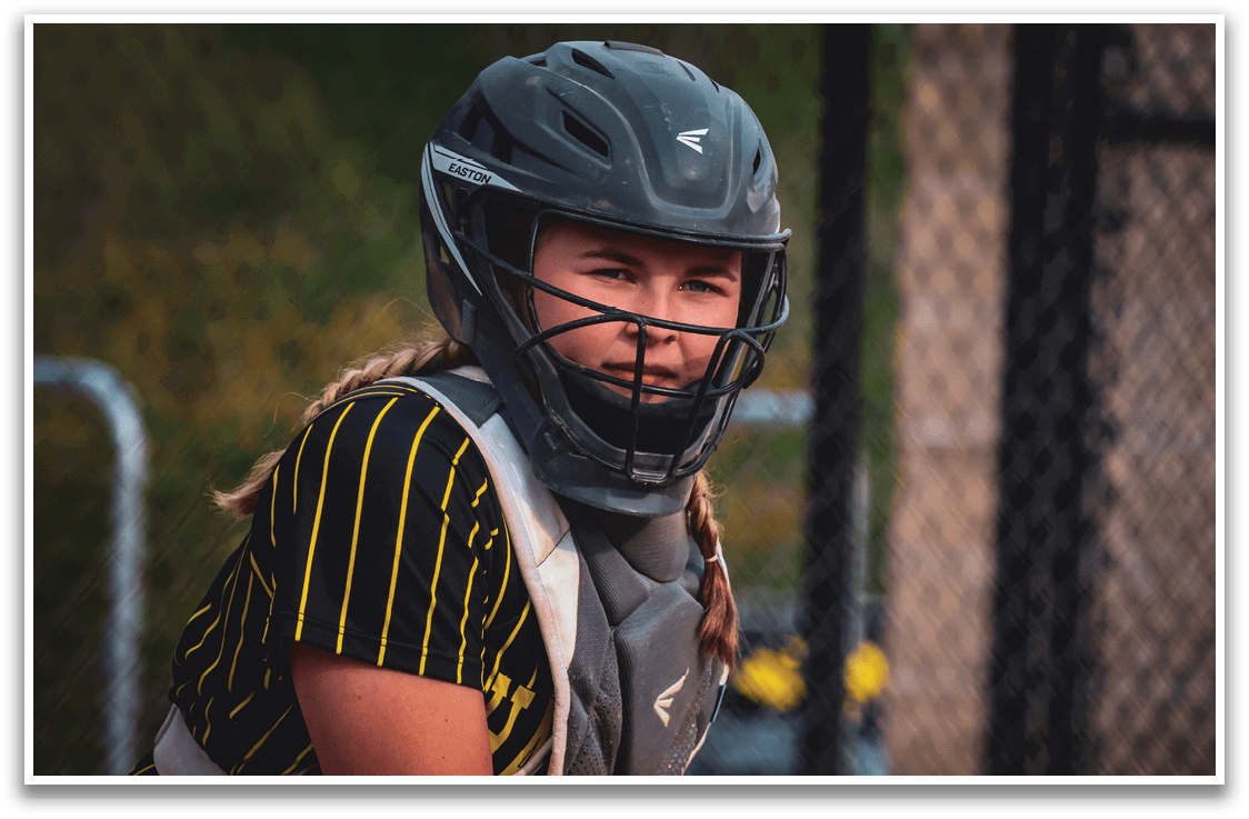 A girl wearing a helmet and catcher's gear. Description generated by AI