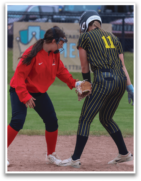 A woman wearing a red shirt and black pants is bending over to help another woman who is wearing a yellow and black shirt. Description generated by AI