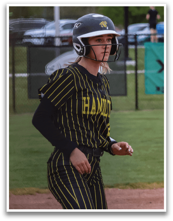 A girl wearing a baseball helmet and a black and yellow jersey. Description generated by AI