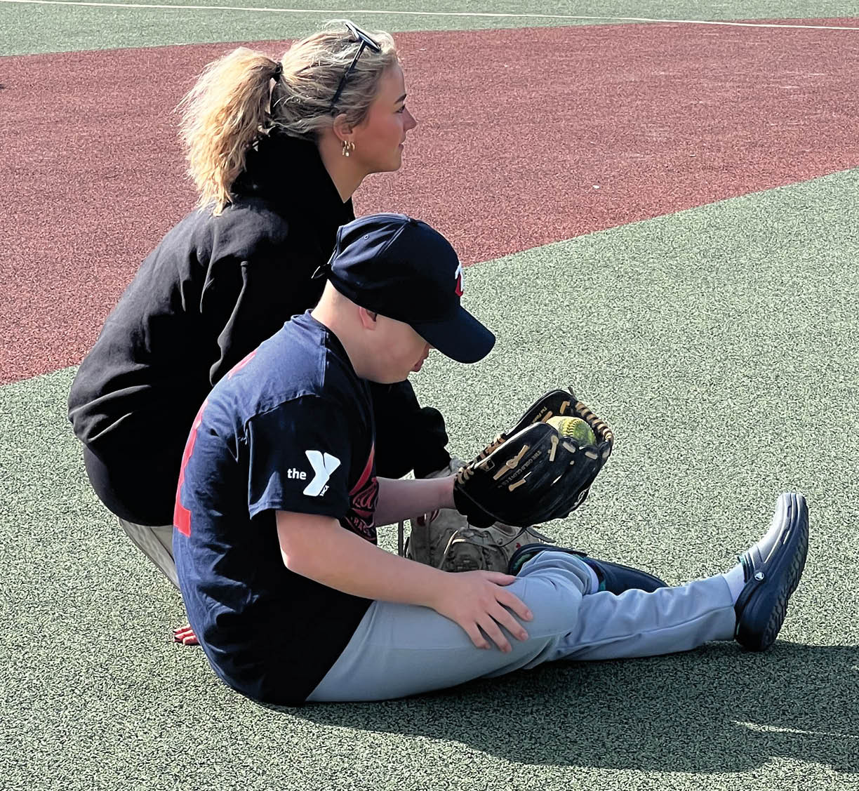 A woman and a boy are sitting on the ground. Description generated by AI