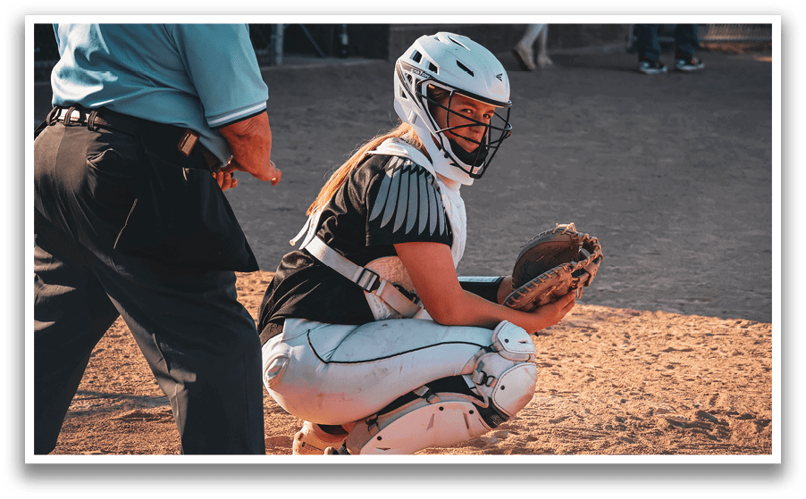 A baseball catcher wearing a helmet and white pants. Description generated by AI