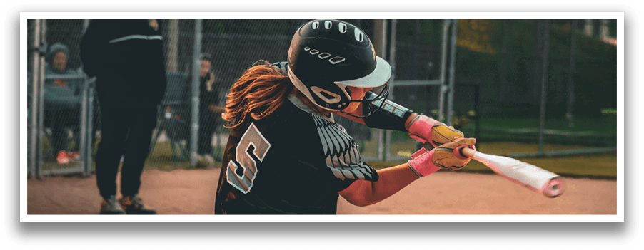 A woman wearing a black and white uniform is swinging a bat at a ball. Description generated by AI
