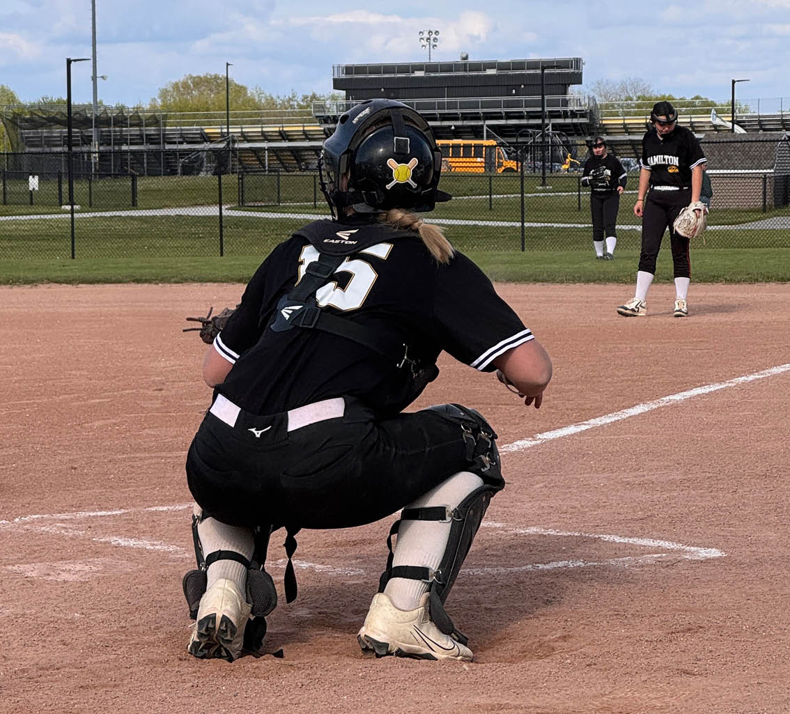 A baseball catcher is squatting behind the home plate. Description generated by AI