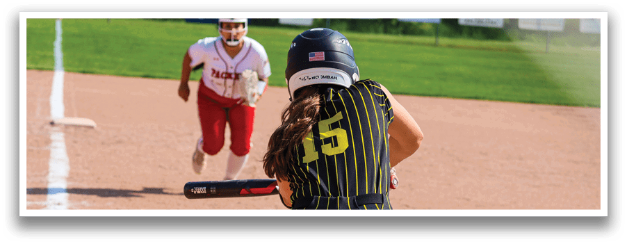 A woman in a black and yellow shirt is swinging a bat at a ball. Description generated by AI