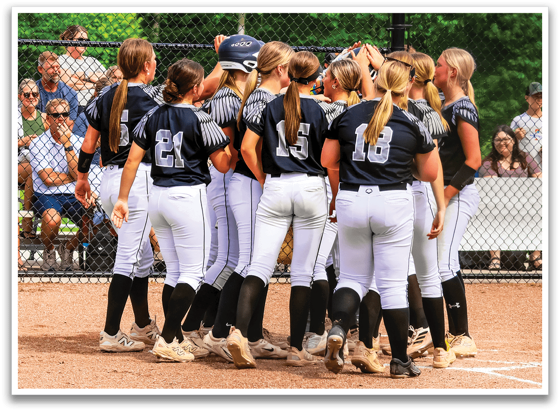 A group of girls wearing black and white uniforms huddle together on a baseball field. Description generated by AI