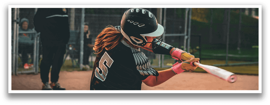 A woman wearing a black and white uniform is swinging a bat at a ball. Description generated by AI