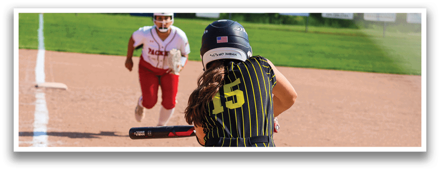 A woman in a black and yellow shirt is swinging a bat at a ball. Description generated by AI