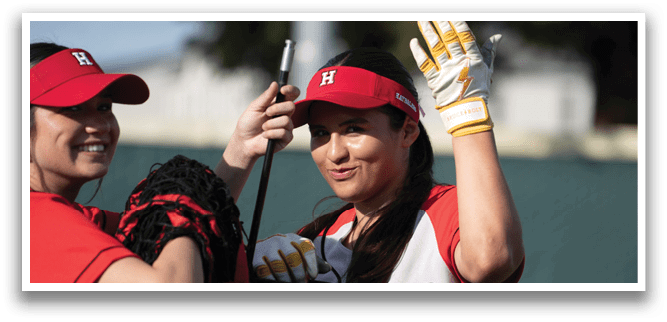 Two women are on a field, one holding a baseball glove and the other holding a bat. They are both wearing baseball uniforms and are smiling. AI generated content