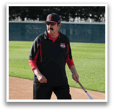 A man wearing a black and red shirt and a black hat stands on a baseball field holding a bat. AI generated content