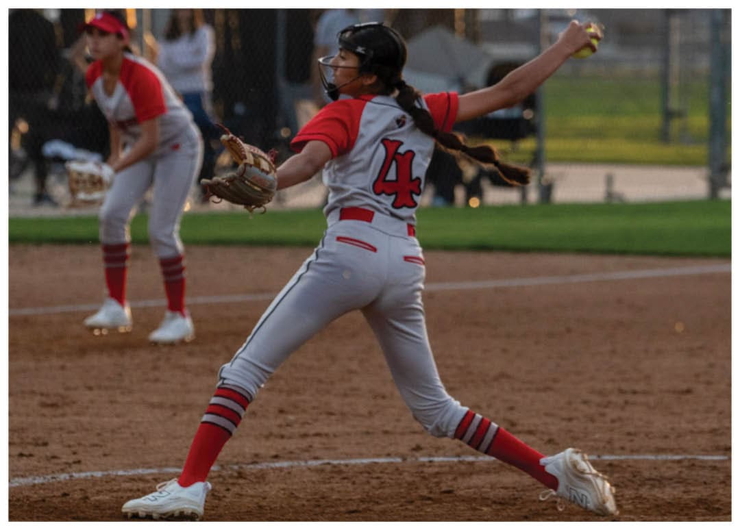 A female baseball player in a red and white uniform is pitching a ball on a field. AI generated content