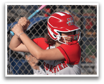 A girl is swinging a bat at a ball. Description generated by AI