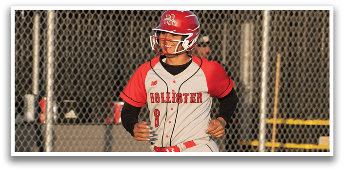 A woman wearing a red and white uniform is walking on a baseball field. Description generated by AI