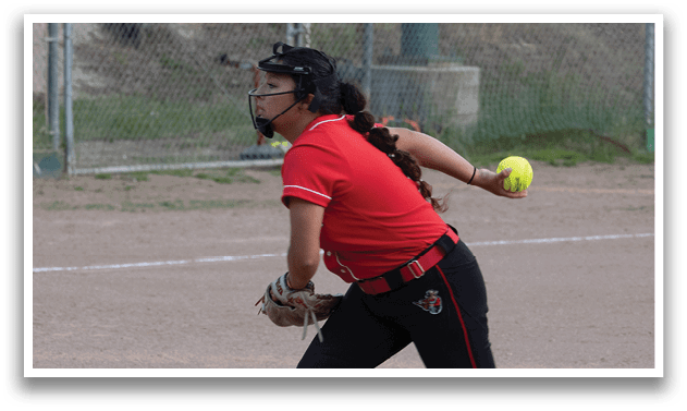 A woman wearing a red shirt and black pants is throwing a ball. Description generated by AI