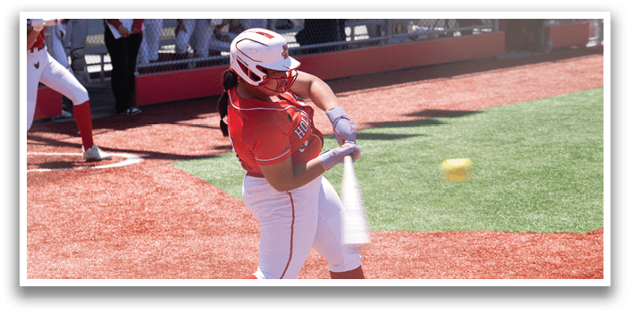 A woman is swinging a bat at a ball. Description generated by AI