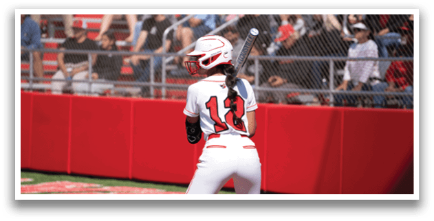 A girl in a white and red baseball uniform is holding a bat. Description generated by AI