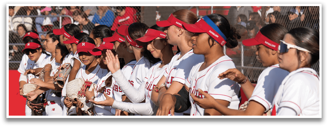 A group of female baseball players standing on a field. Description generated by AI