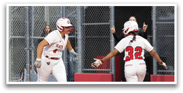 Two female baseball players wearing red and white uniforms. Description generated by AI