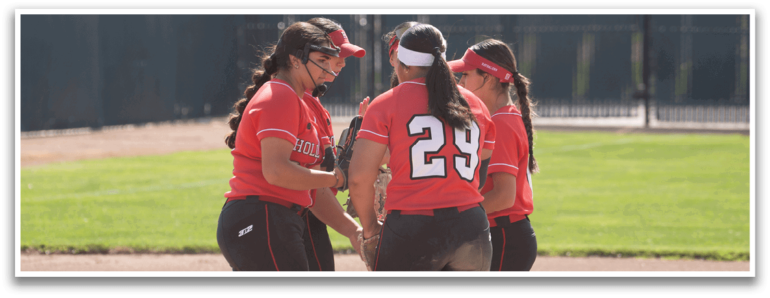 A group of girls in white and red uniforms pose for a picture on a baseball field. Description generated by AI