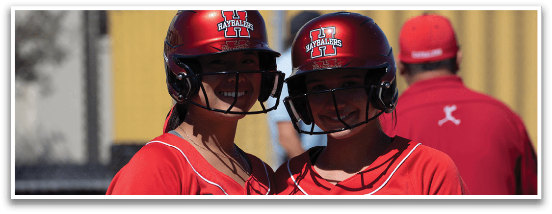 A group of female baseball players standing on a field. Description generated by AI