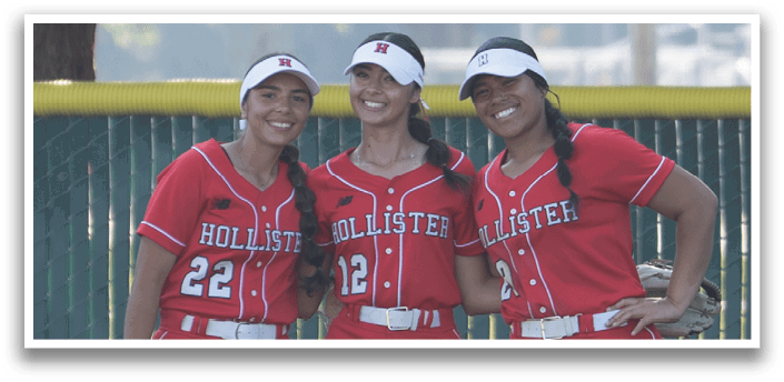 Three female softball players wearing red uniforms and white socks stand on a baseball field. AI generated content