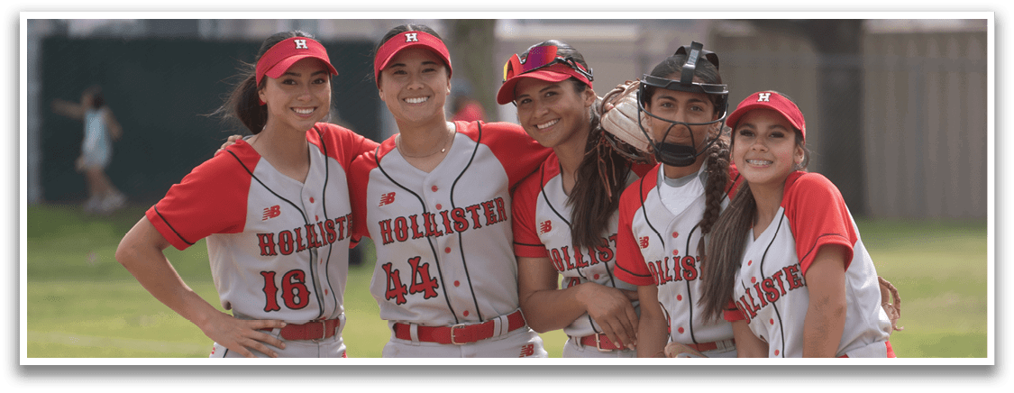 A group of five female softball players pose for a picture on the field. AI generated content