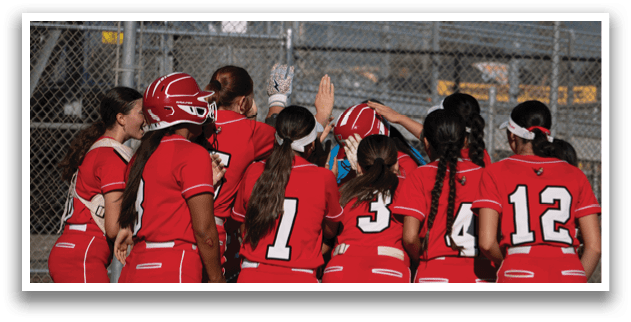 A group of girls wearing red uniforms are huddled together on a baseball field. AI generated content