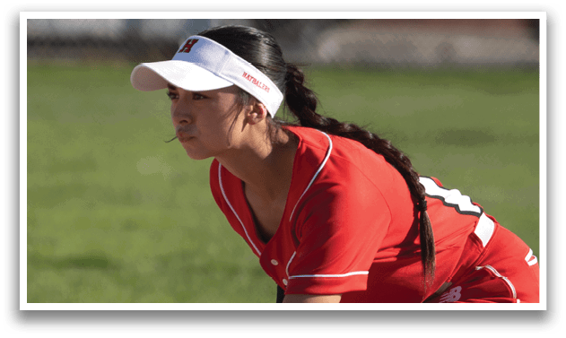A female baseball player is crouching on the field, wearing a red and white uniform and a catcher's mitt. AI generated content