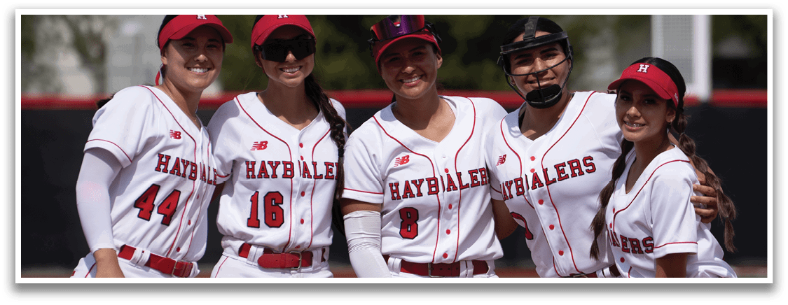 Four female baseball players pose for a picture on the field. AI generated content