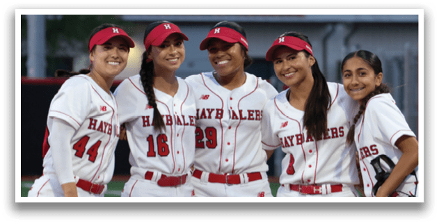 A group of four female softball players pose for a picture on the field. AI generated content