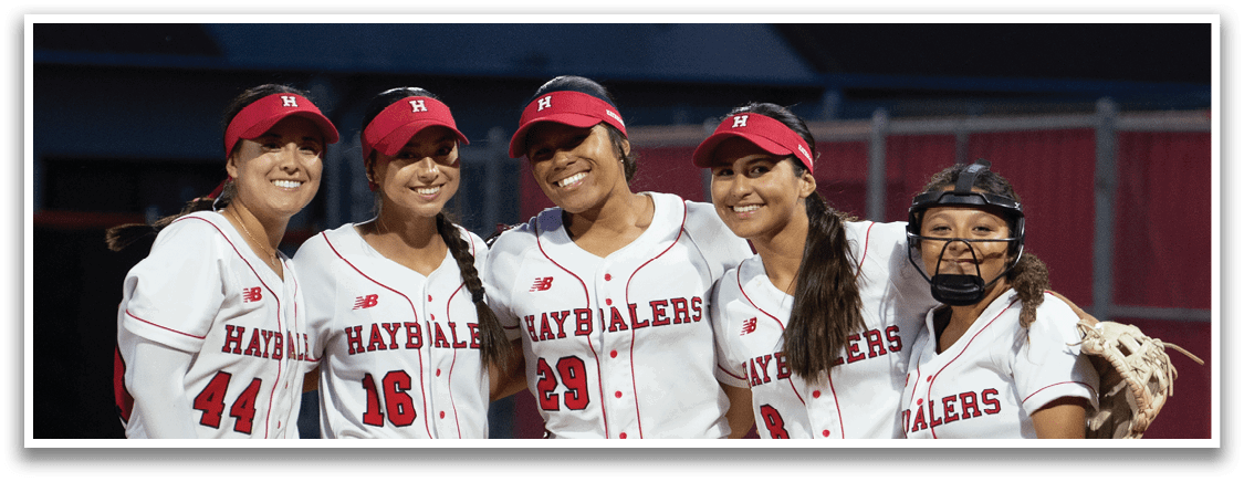 Four female softball players pose for a picture on the field. AI generated content